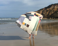 Remnant quilt blowing in the wind, made from reclaimed fabrics. Hand made in Naarm / Melbourne by Britta Rouse