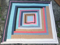 multi-coloured housetop quilt laying flat on the ground