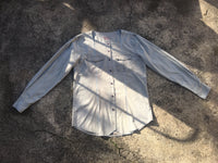 repurposed grey shirt with pale blue stripe, square neckline and patch pockets laying flat on the ground